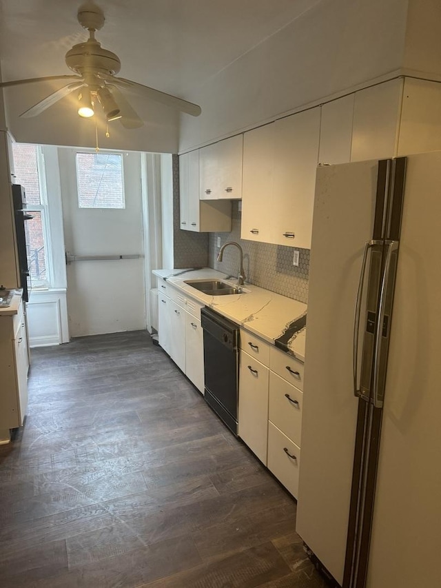 kitchen with dishwasher, a sink, freestanding refrigerator, and white cabinetry