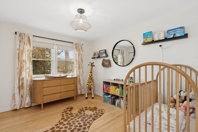 bedroom featuring a crib and light wood-type flooring