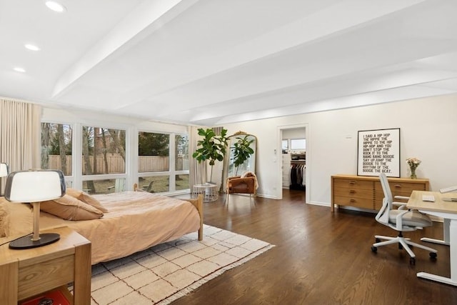 bedroom with a walk in closet, beam ceiling, and hardwood / wood-style floors