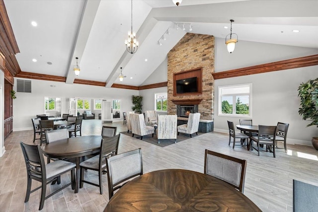 dining area with high vaulted ceiling, a chandelier, a fireplace, beamed ceiling, and light wood-type flooring