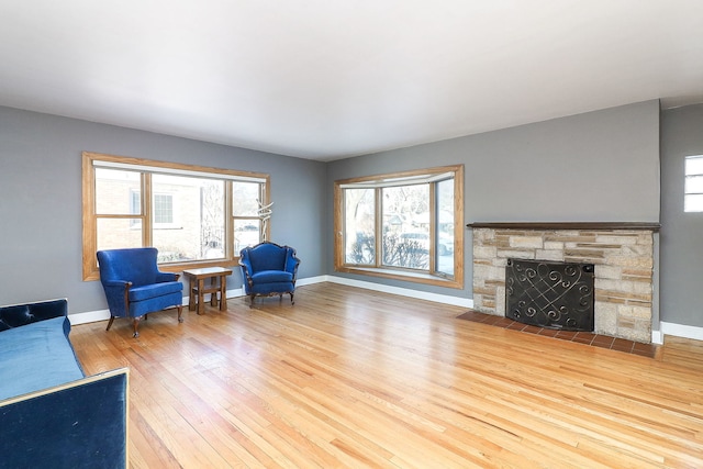 living area with a fireplace, light hardwood / wood-style floors, and a wealth of natural light