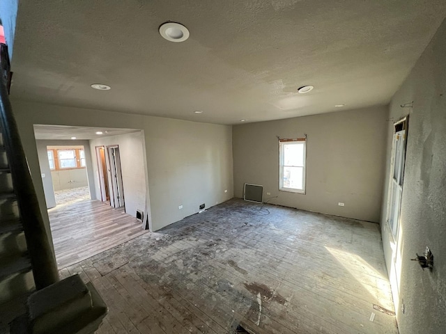 empty room with a textured ceiling and light wood-type flooring