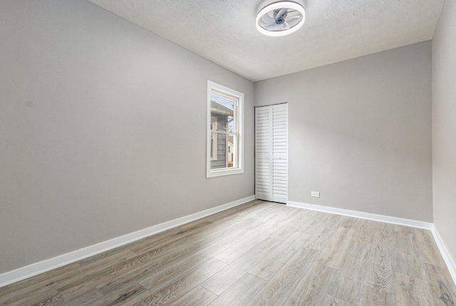 empty room featuring a textured ceiling and light wood-type flooring