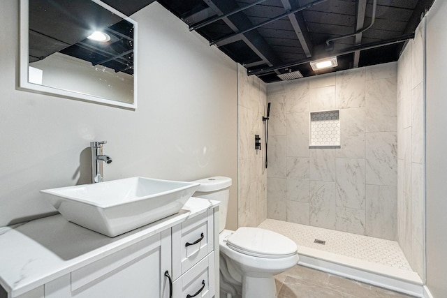 bathroom featuring vanity, tiled shower, and toilet