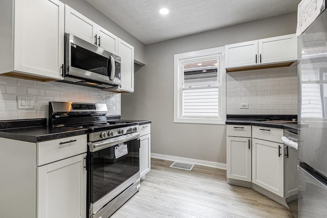 kitchen with white cabinetry, stainless steel appliances, light hardwood / wood-style floors, and a textured ceiling