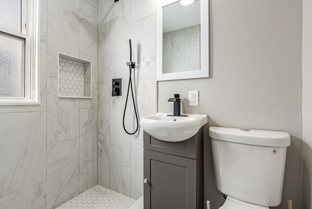 bathroom with vanity, a tile shower, and toilet