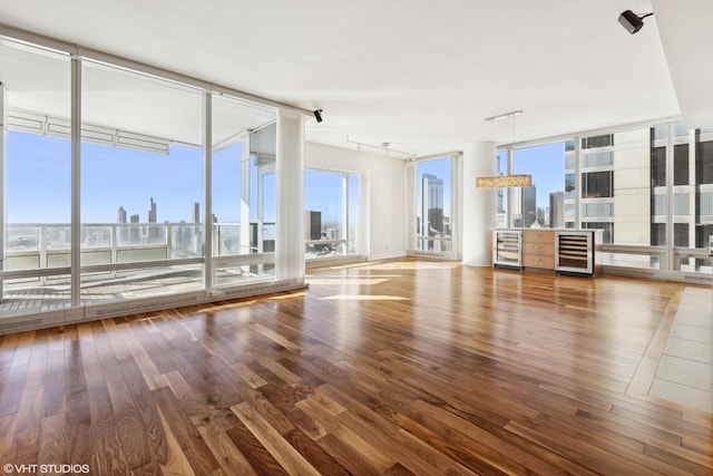 unfurnished living room with beverage cooler, floor to ceiling windows, and a city view