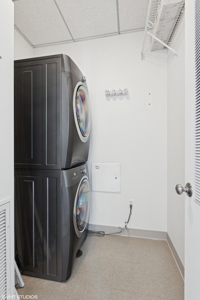 laundry room with laundry area, baseboards, and stacked washing maching and dryer