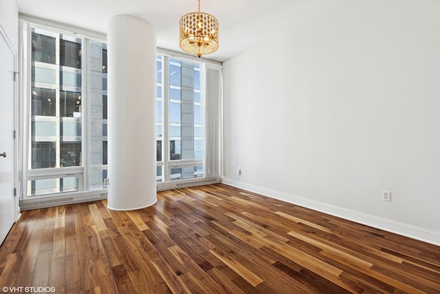 empty room with a wall of windows, dark wood-type flooring, baseboards, and an inviting chandelier