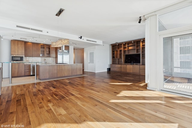 kitchen featuring visible vents, open floor plan, appliances with stainless steel finishes, light wood-type flooring, and brown cabinetry