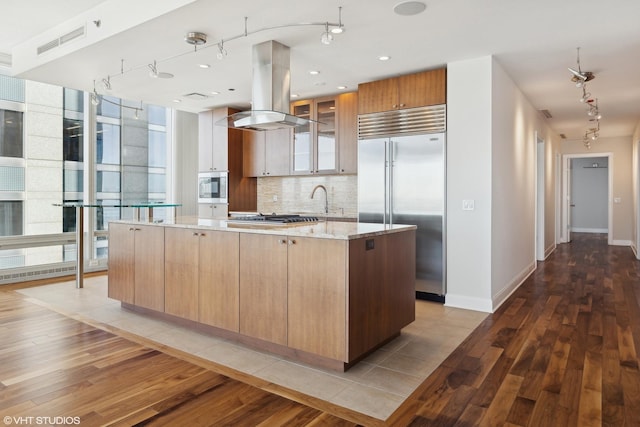 kitchen with stainless steel appliances, visible vents, decorative backsplash, light wood finished floors, and island exhaust hood