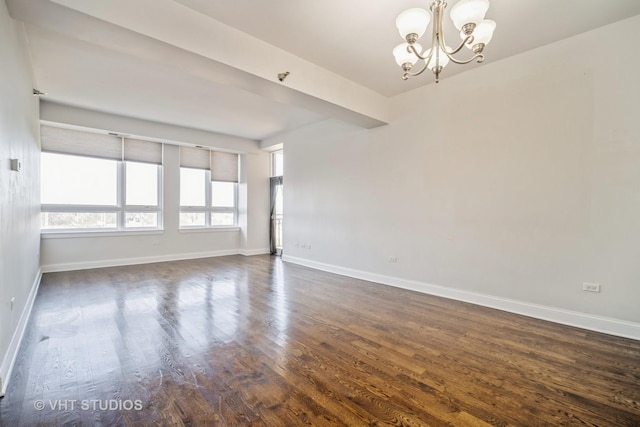 empty room featuring an inviting chandelier and dark hardwood / wood-style floors