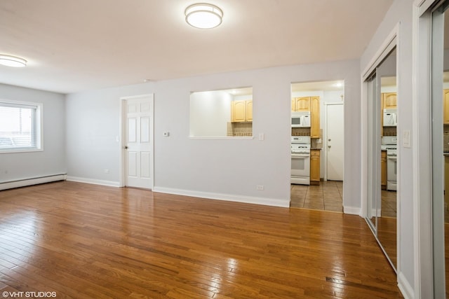 empty room with a baseboard heating unit and light wood-type flooring