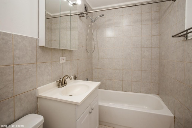 full bathroom featuring vanity, tiled shower / bath, tile walls, and toilet