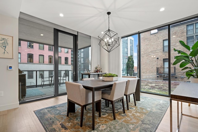 dining space featuring a notable chandelier, light hardwood / wood-style flooring, expansive windows, and a healthy amount of sunlight