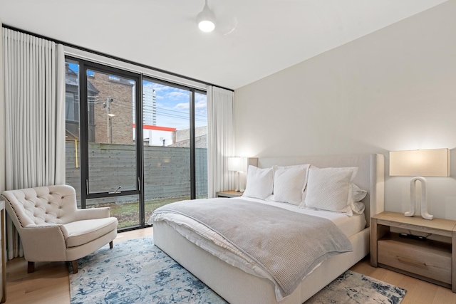 bedroom with floor to ceiling windows, access to exterior, and light hardwood / wood-style floors