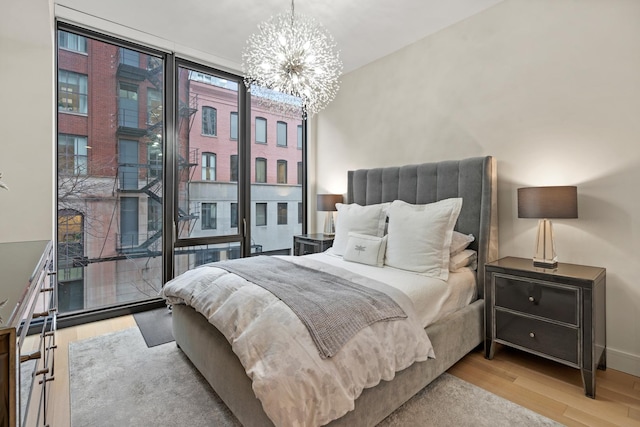 bedroom with expansive windows, a chandelier, and light hardwood / wood-style floors