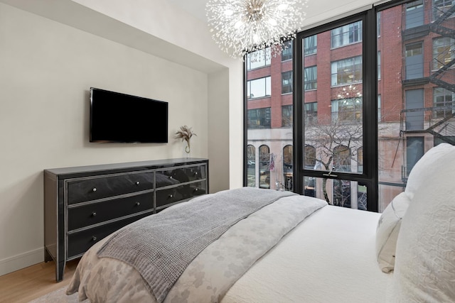 bedroom with wood-type flooring, floor to ceiling windows, and a notable chandelier