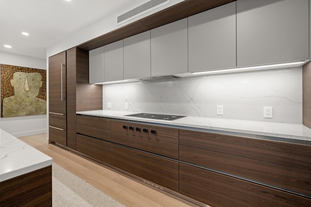 kitchen with white cabinetry, black gas cooktop, tasteful backsplash, light hardwood / wood-style floors, and light stone countertops