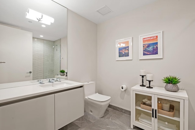 bathroom with vanity, a shower with door, and toilet