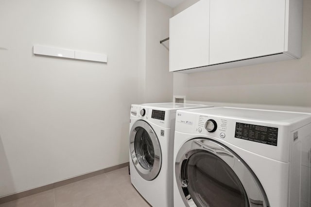 washroom featuring cabinets, light tile patterned flooring, and washer and dryer