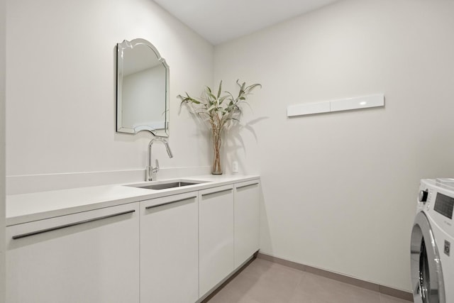 clothes washing area with cabinets and sink