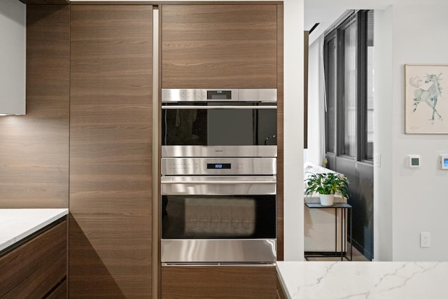 kitchen with light stone countertops and stainless steel double oven