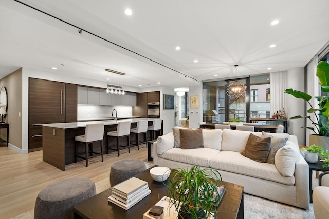 living room with a chandelier, sink, and light wood-type flooring