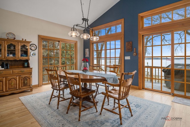 dining area with high vaulted ceiling, a chandelier, and light hardwood / wood-style flooring