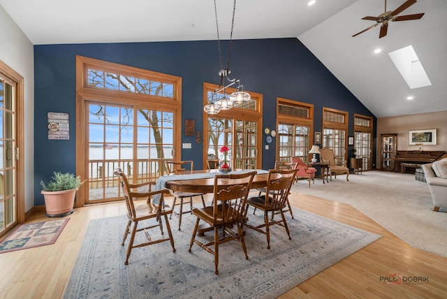 dining room featuring hardwood / wood-style floors, a wealth of natural light, high vaulted ceiling, and a skylight