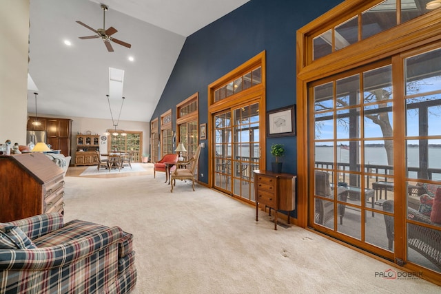 living area with carpet floors, high vaulted ceiling, ceiling fan, and a water view