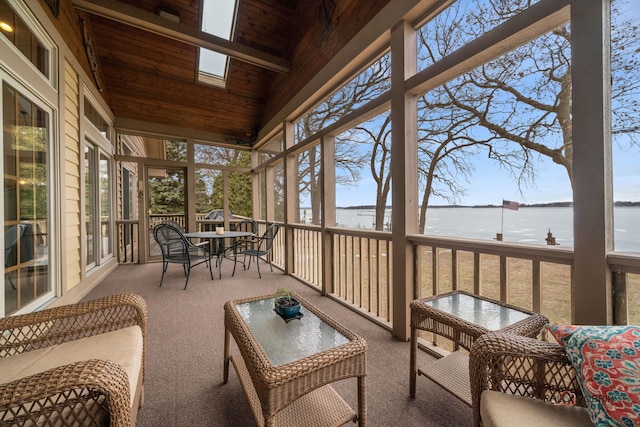 sunroom / solarium featuring vaulted ceiling with skylight and a water view