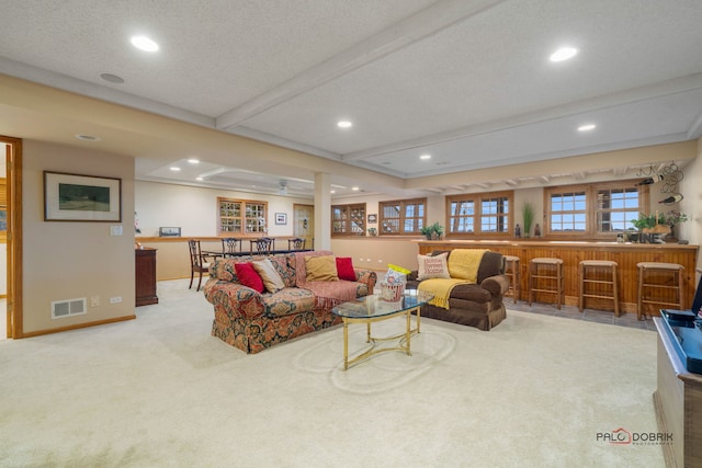 living room featuring light carpet, beam ceiling, a textured ceiling, and indoor bar