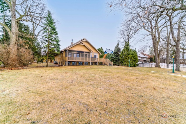 rear view of house with a wooden deck, a sunroom, and a lawn