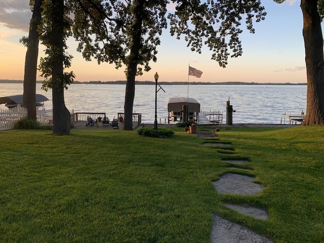 view of dock with a water view and a lawn