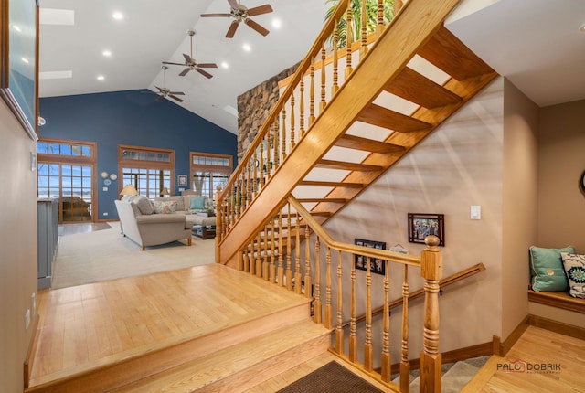 staircase with wood-type flooring and high vaulted ceiling