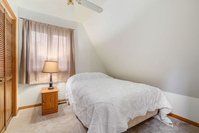 bedroom featuring ceiling fan, a closet, lofted ceiling, and light carpet