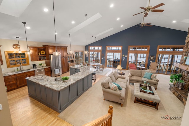 living room with high vaulted ceiling, a wealth of natural light, sink, and light wood-type flooring