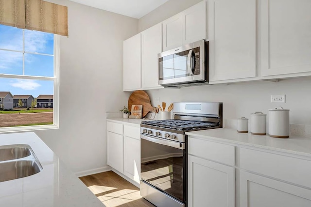 kitchen featuring sink, stainless steel appliances, white cabinets, and light wood-type flooring