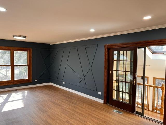 empty room with ornamental molding, wood-type flooring, and a skylight