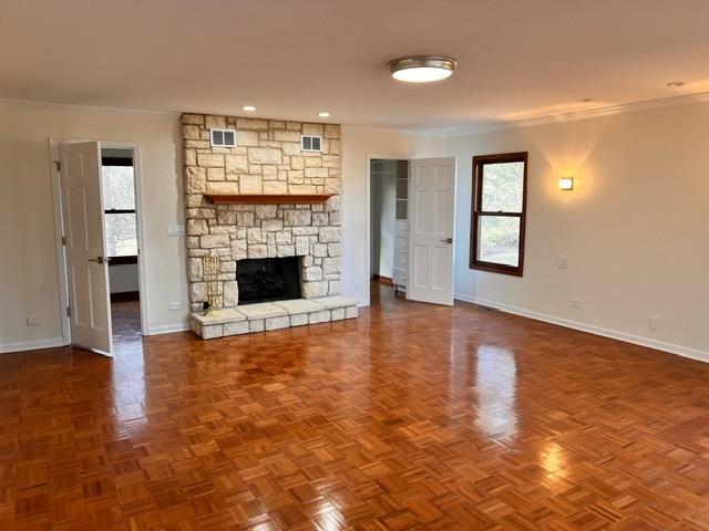 unfurnished living room featuring crown molding, parquet flooring, and a fireplace