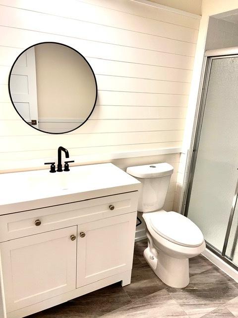 bathroom featuring vanity, hardwood / wood-style floors, a shower with door, and toilet