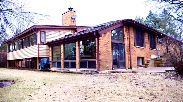 view of side of home with a patio and a sunroom