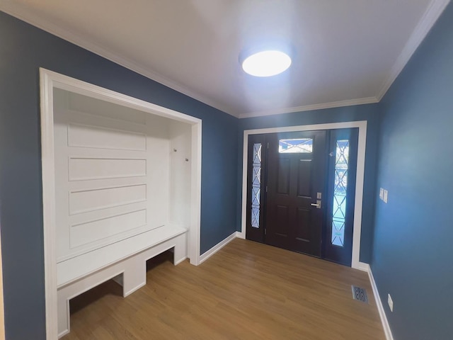 entryway with ornamental molding and hardwood / wood-style floors