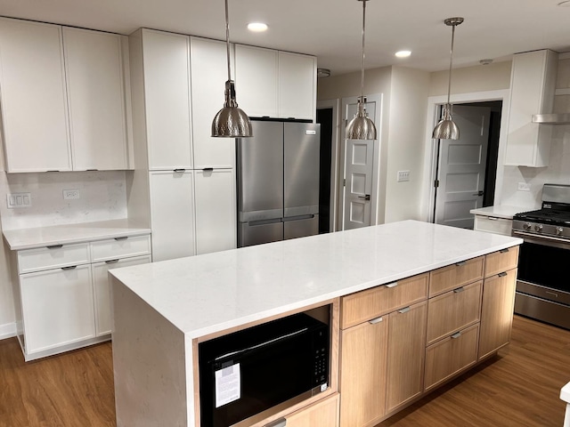 kitchen with white cabinetry, stainless steel appliances, a kitchen island, and light wood-type flooring