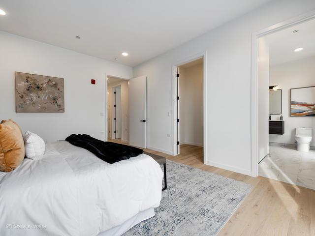 bedroom with ensuite bathroom and light hardwood / wood-style flooring