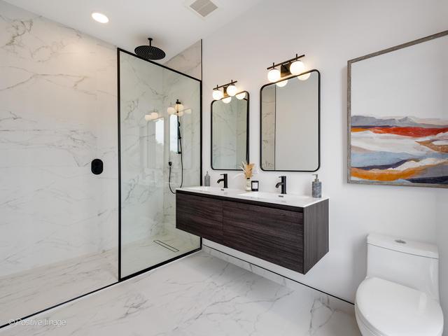 bathroom featuring a tile shower, vanity, and toilet