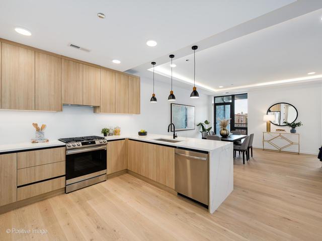 kitchen with sink, kitchen peninsula, stainless steel appliances, light brown cabinets, and light hardwood / wood-style flooring