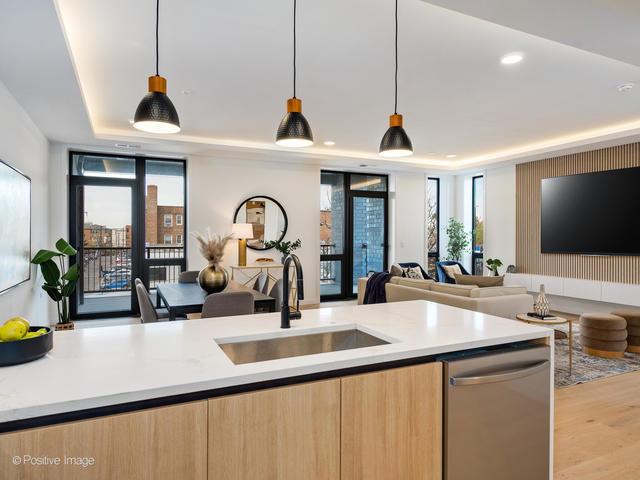 kitchen featuring stainless steel dishwasher, a tray ceiling, decorative light fixtures, and sink