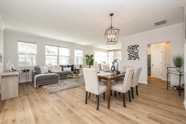 dining space featuring crown molding, light hardwood / wood-style flooring, and a notable chandelier